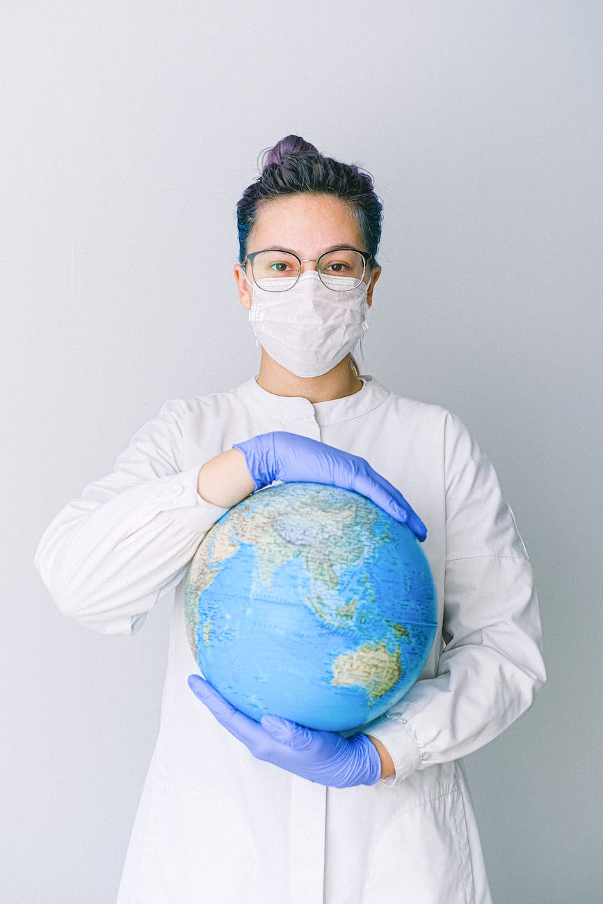 person with a face mask and latex gloves holding a globe